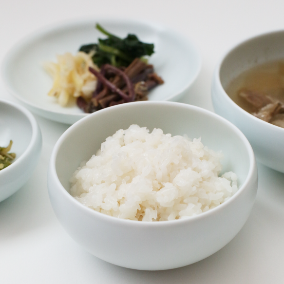 White ceramic one-person bowl set with rice and side servings in small bowls