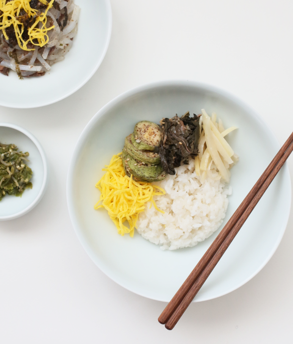 Light gray round ceramic salad bowl with rice, vegetables, and wooden chopsticks