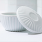 White porcelain lidded container with ribbed lid, lid leaned beside bowl