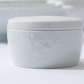 White porcelain lidded container with embossed floral pattern on lid and body