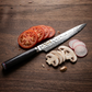 Pairing knife with decorative metal blade next to sliced tomato, mushrooms
