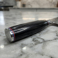 Pairing knife wrapped in protective sleeve, dark handle with red accent bands