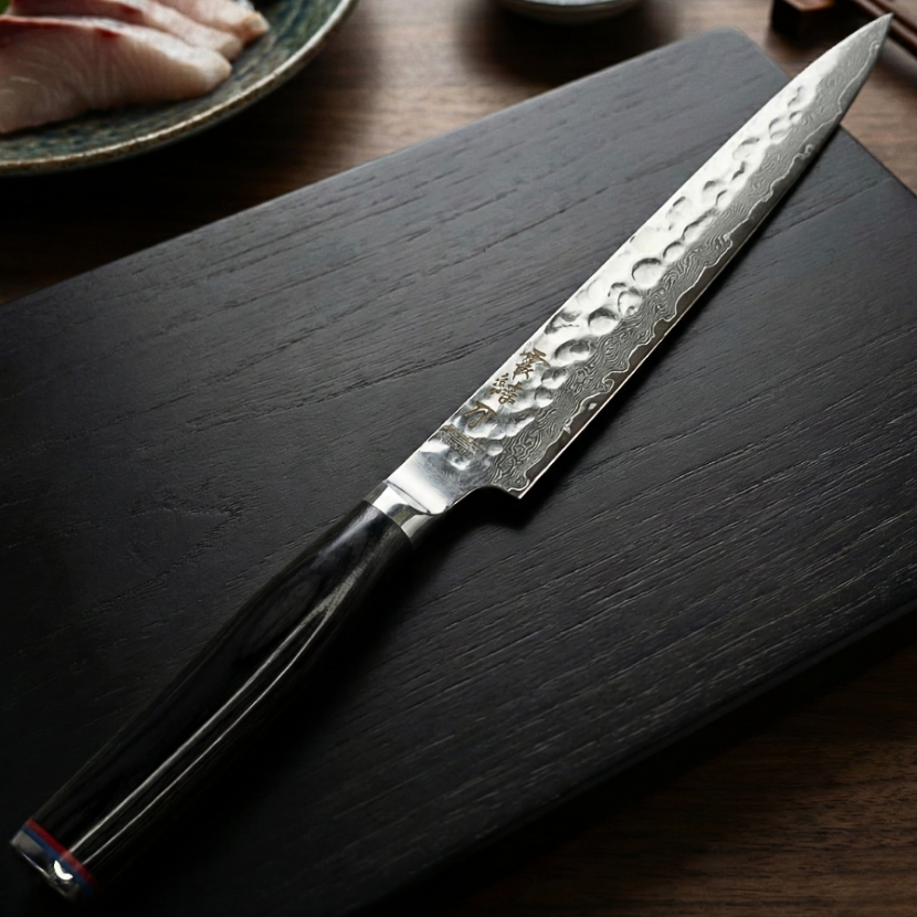 Pairing knife with dark handle and hammered blade on a dark wooden surface