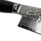 Damascus chef knife close-up with black handle and hammered blade pattern