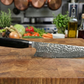 Damascus-style chef knife with black handle on wooden cutting board