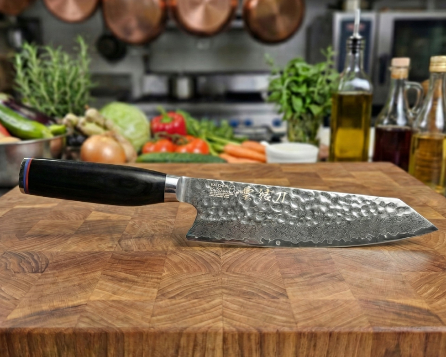 Damascus-style chef knife with black handle on wooden cutting board
