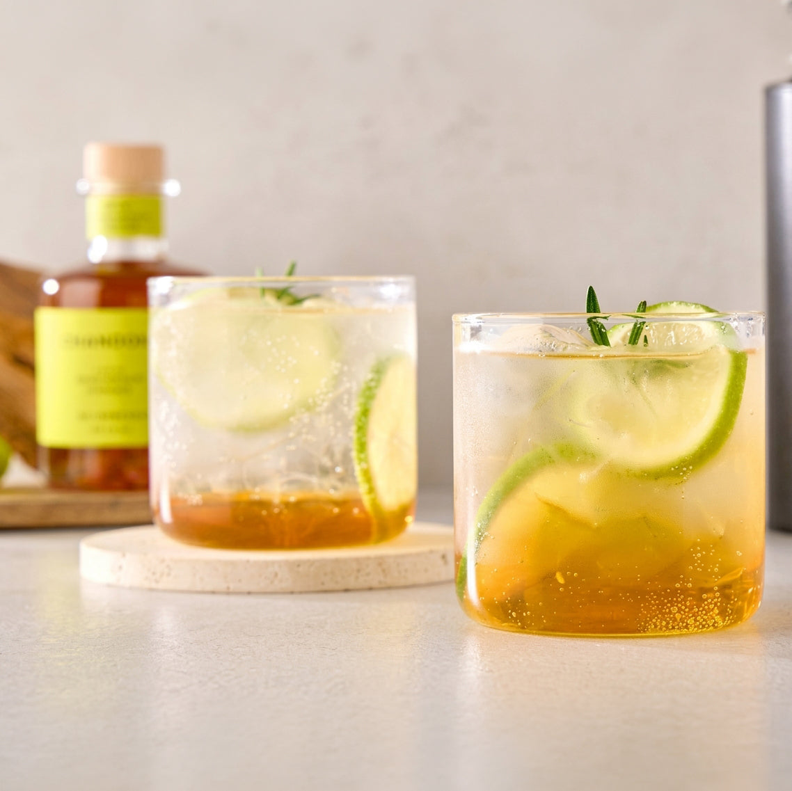 Shine Bianco vinegar bottle with two iced drink glasses and cucumber slices