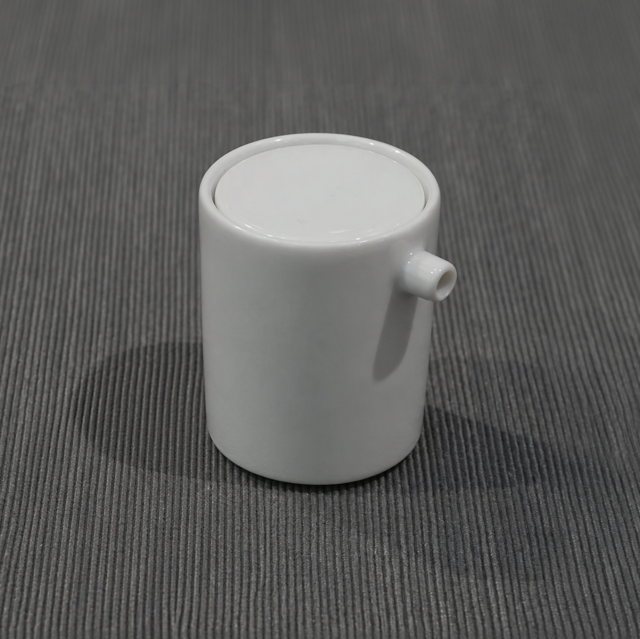 White ceramic candle jar with round lid and small side spout