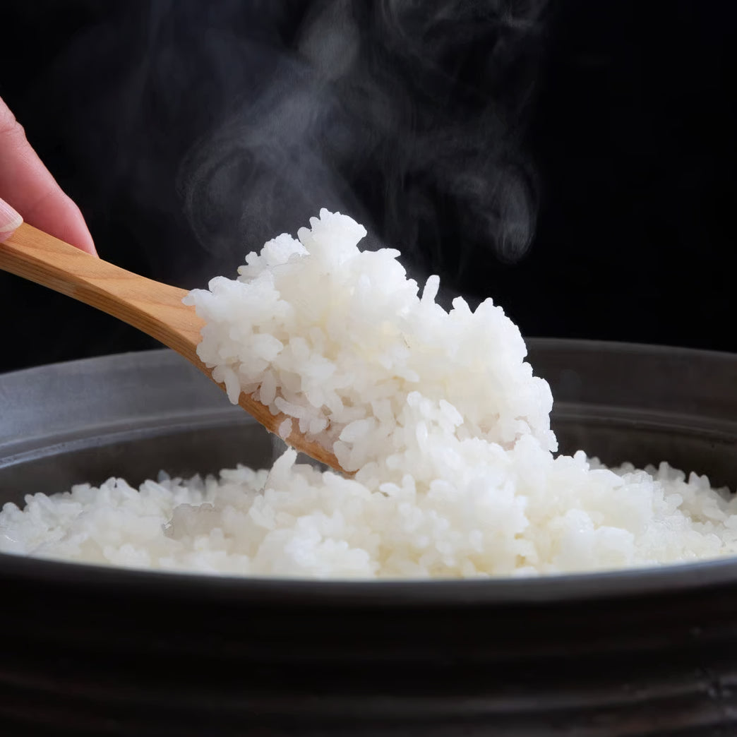 Steaming white rice in a bowl with a wooden serving spoon