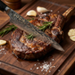 Pairing knife slicing a steak with rosemary on a wooden serving board
