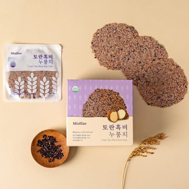 Black rice taro chips beside pouch, box, and small bowl of seeds