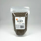 Roasted perilla seeds in a clear stand-up pouch, dark gray-green whole seeds