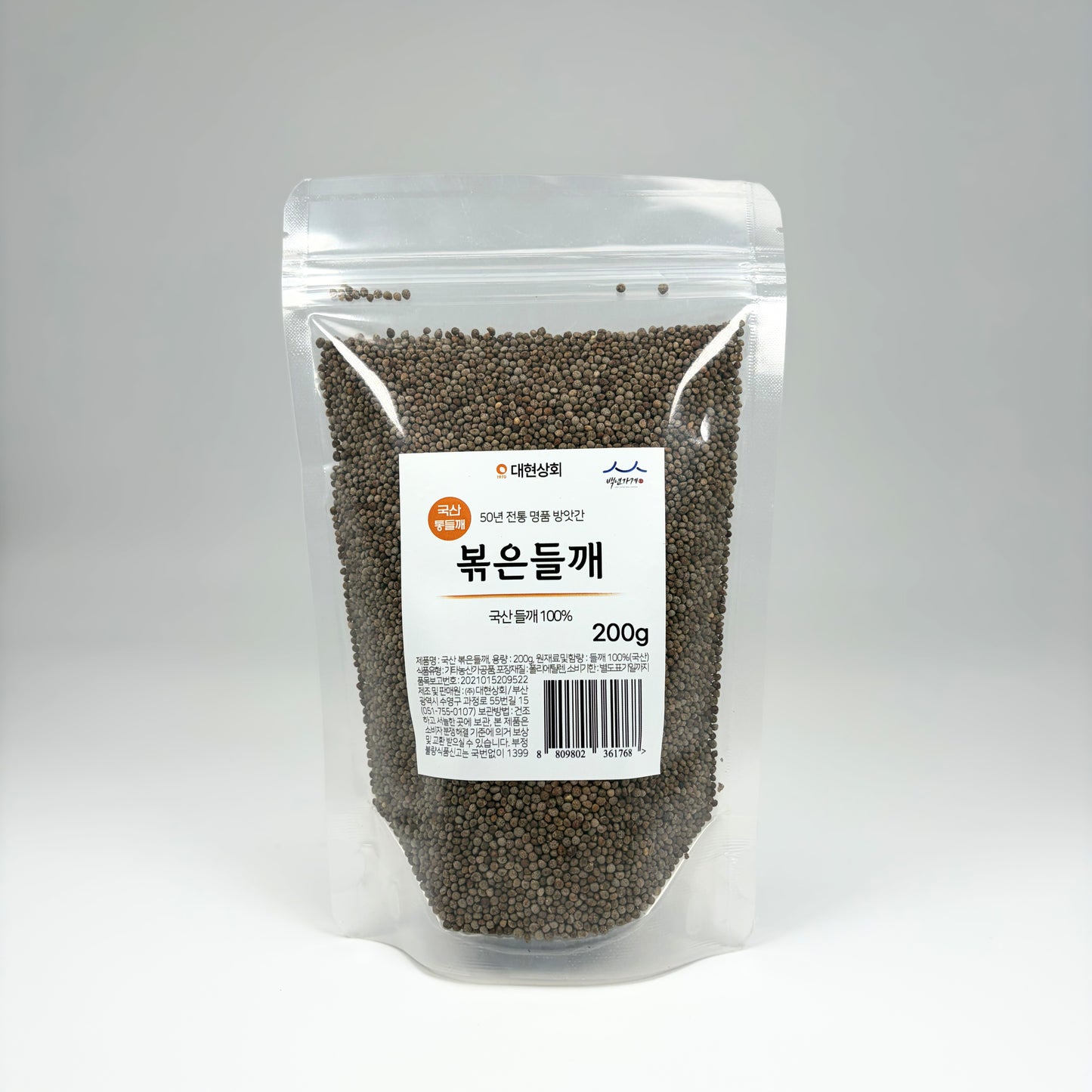 Roasted perilla seeds in a clear stand-up pouch, dark gray-green whole seeds