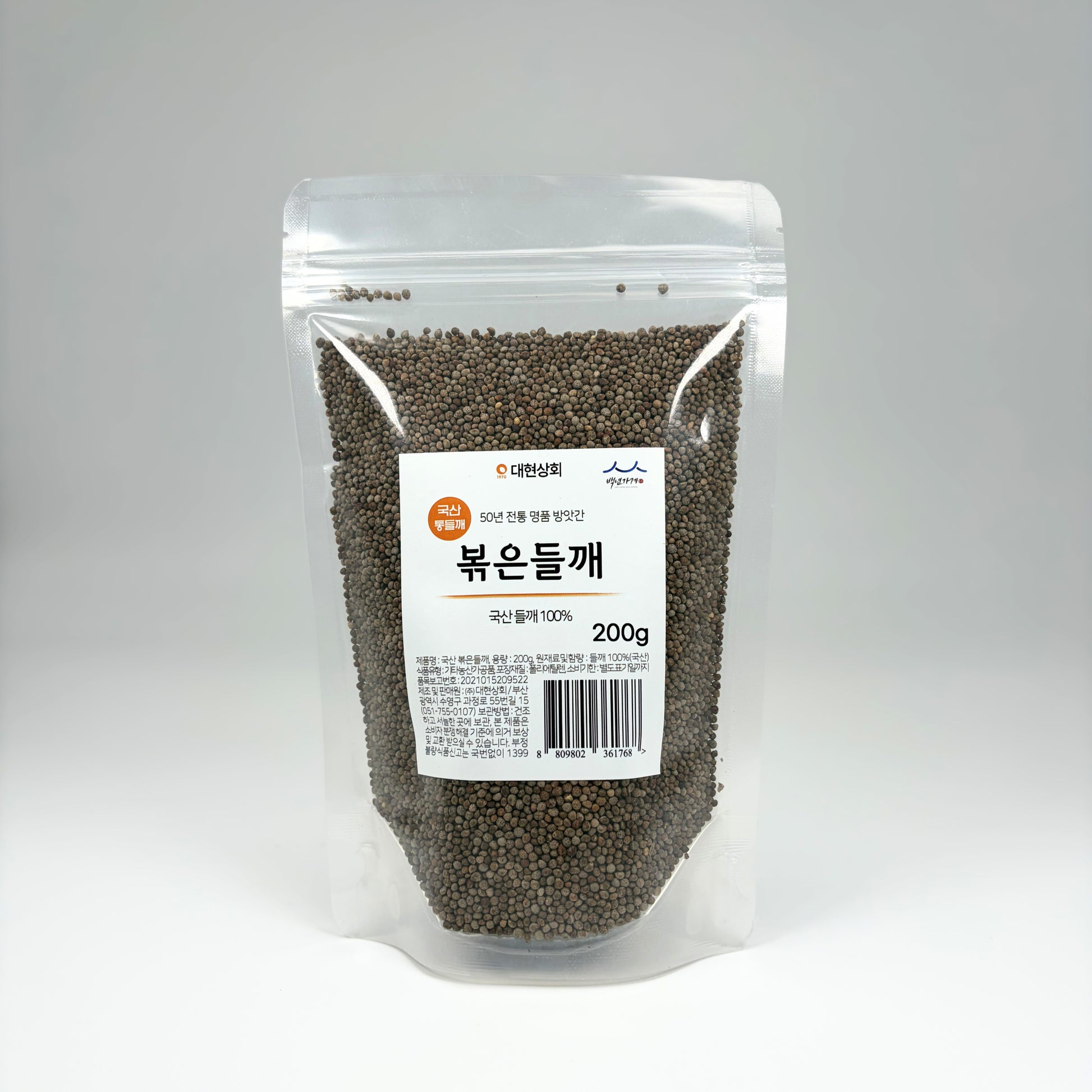 Roasted perilla seeds in a clear stand-up pouch, dark gray-green whole seeds
