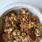 Dark granola in a speckled bowl with nuts and seed clusters
