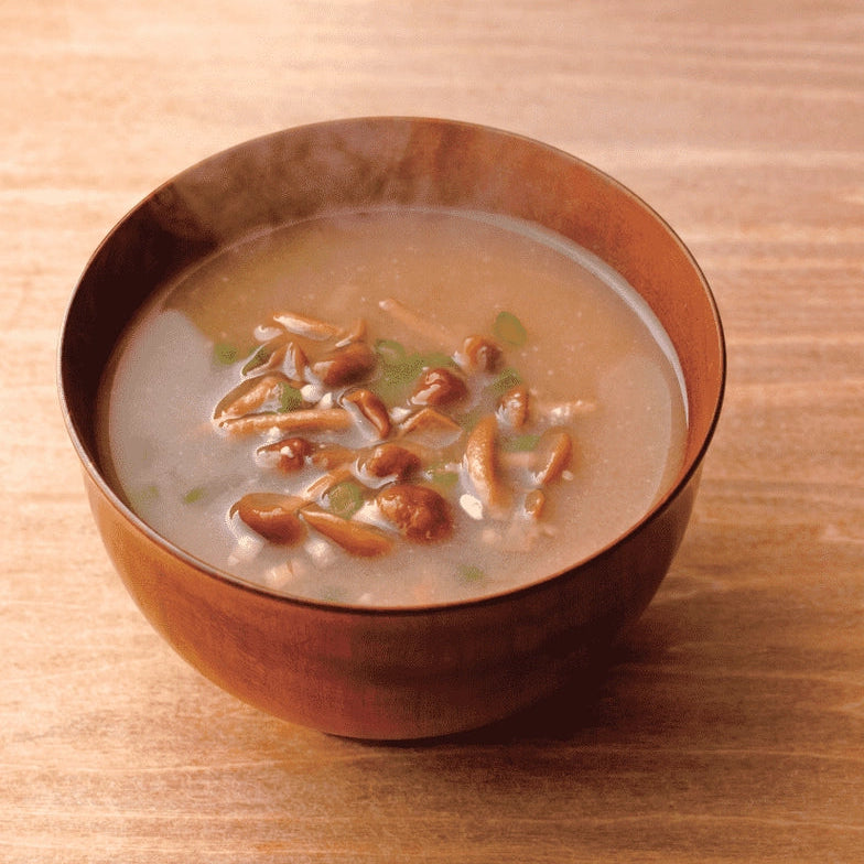 Bowl of light miso soup with seaweed pieces and green onion