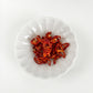 Dried red pepper pieces in a white bowl