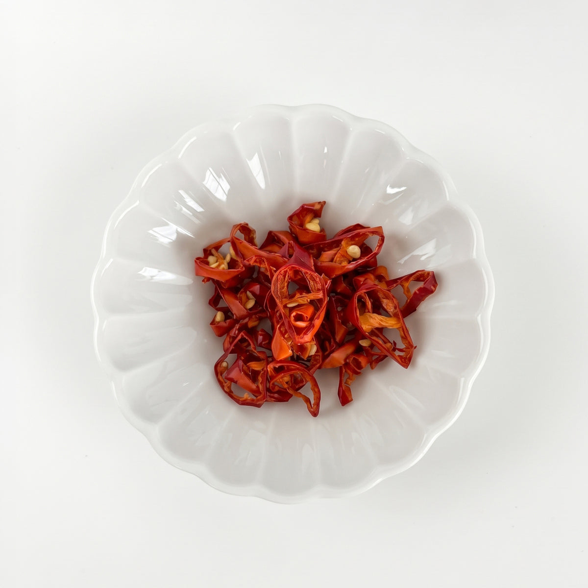 Dried red pepper pieces in a white bowl