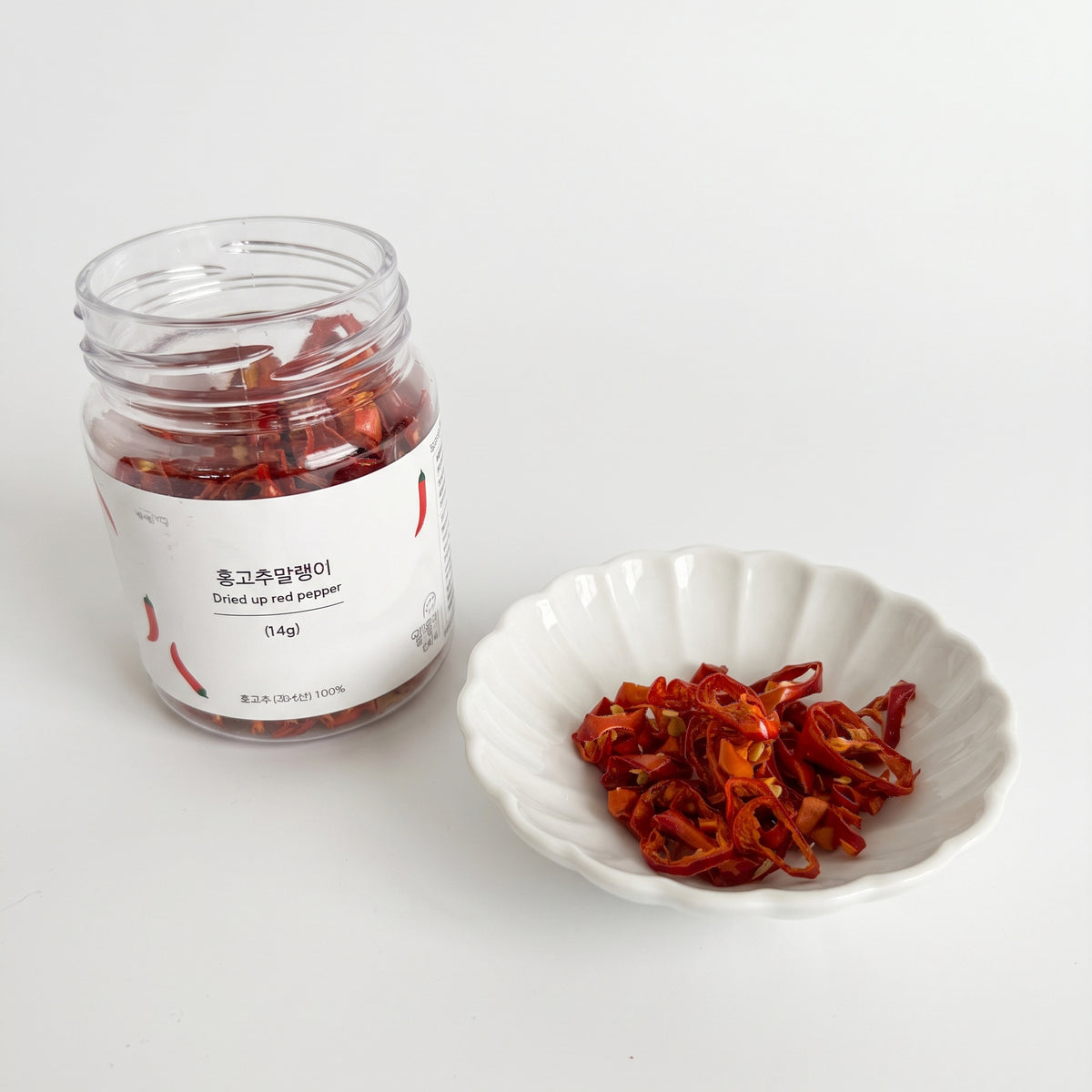 Dried red pepper jar and dried red pepper pieces in a white bowl