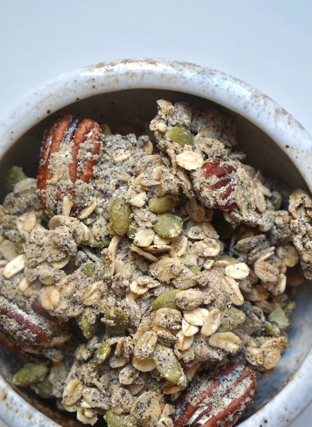 Granola in a speckled bowl with oats, seeds, and dried fruit bits