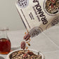 Earl Grey Yuzu granola bag with bowl of granola and a glass bottle nearby