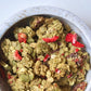 Green granola in a speckled bowl with red strawberry pieces