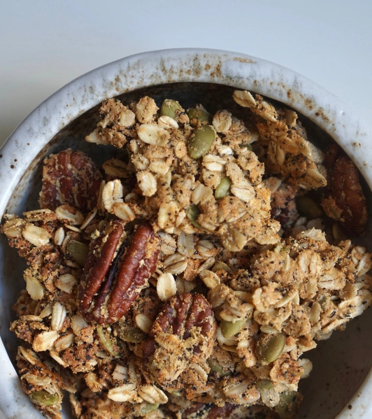 Granola in a speckled bowl with nuts, seeds, and dried fruit pieces